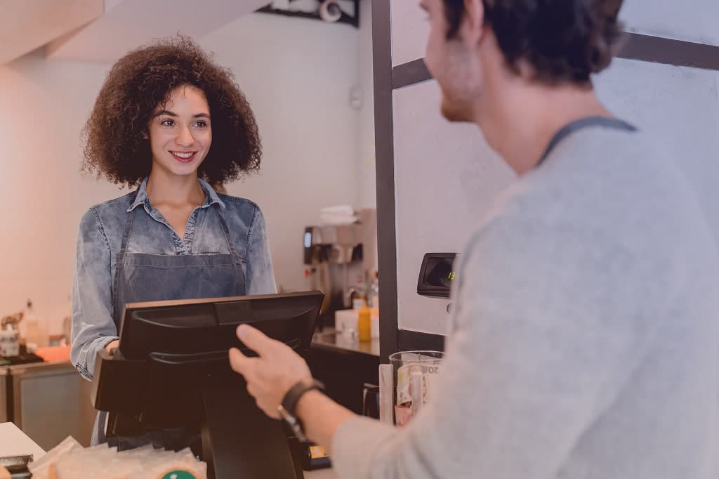 Image of an employee at the counter smiling at a customer.