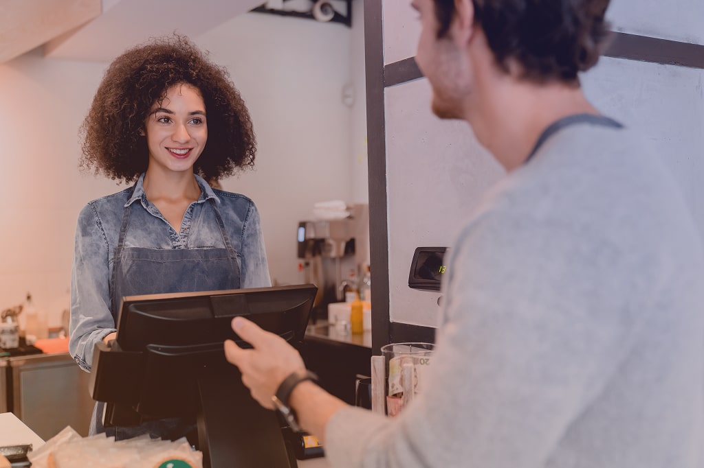 Image of an employee at the counter smiling at a customer.
